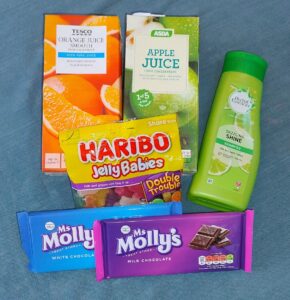 Photo of orange and apple juice, haribo sweets, chocolate bars and shampoo